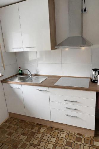 a kitchen with white cabinets and a sink at Pension am Heckenacker in Rothenburg ob der Tauber