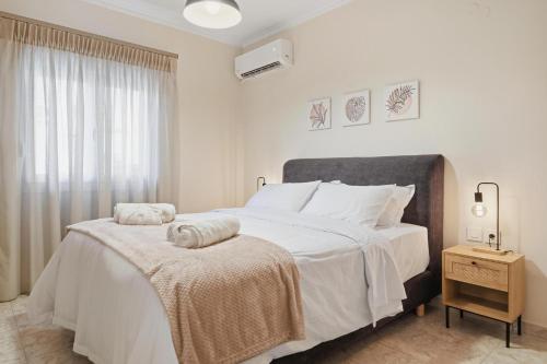 a white bedroom with a large bed with towels on it at Calma Ioannina Apartment in Ioannina