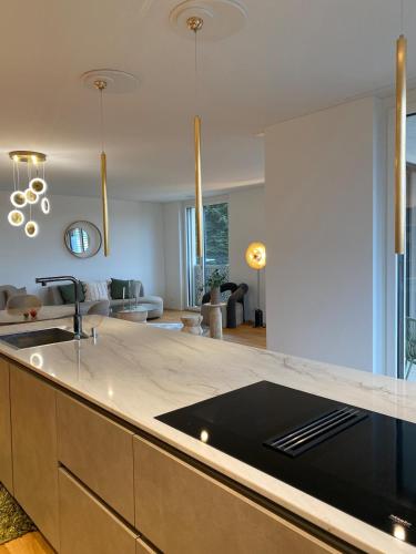 a kitchen with a counter top and a living room at New and elegant luxury apartment in Kloten