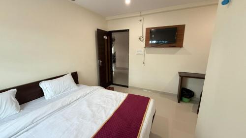 a bedroom with a bed and a tv on the wall at JJ Comfort Hotel in Turuvekere