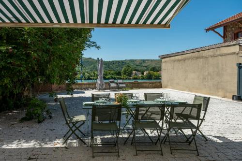 a patio with a table with chairs and an umbrella at L'Escale du Rhône de 1 à 8 personnes in Saint-Vallier