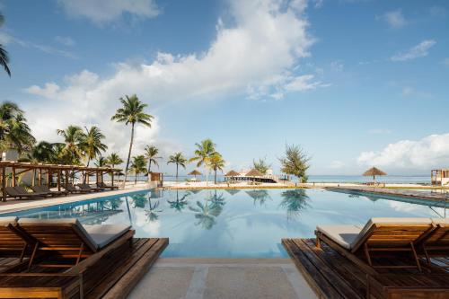 a pool with chairs and the ocean in the background at JAZ Elite Aurora in Michamvi