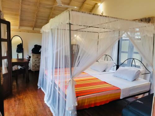a bedroom with a bed with a canopy at Pilgrims Nature Villa in Ahangama