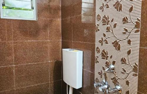 a bathroom with a toilet paper dispenser on a wall at The Lotus in Pune