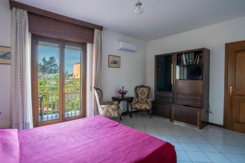 a bedroom with a bed and a tv and a balcony at Casa Wanda IL MIRTO in Oristano