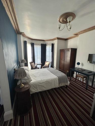 a bedroom with a bed and a table and a lamp at Morlea Guest House in Llandudno
