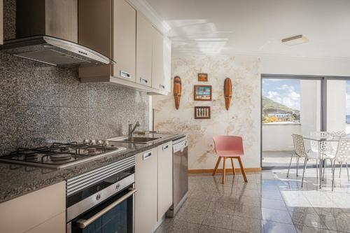 a kitchen with a sink and a stove top oven at Beachfront Penthouse with Panoramic Ocean-View Terrace VIP Baia in Machico