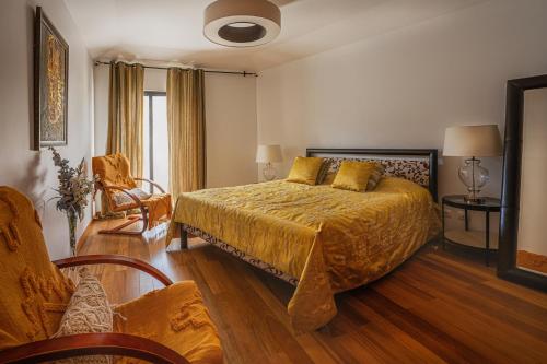 a bedroom with a king sized bed and a chair at Beachfront Penthouse with Panoramic Ocean-View Terrace VIP Baia in Machico