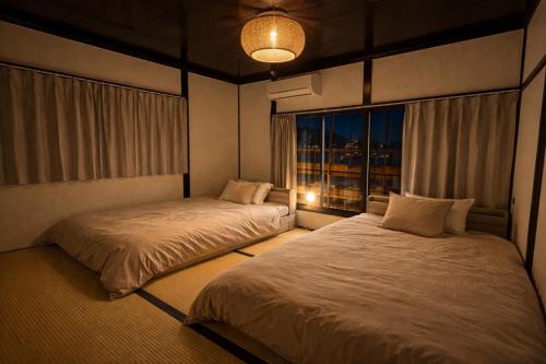 two beds in a room with a window at Nagasaki Night View Terrace Entire Home -Inasayama Panorama稲佐山夜景テラス in Nagasaki