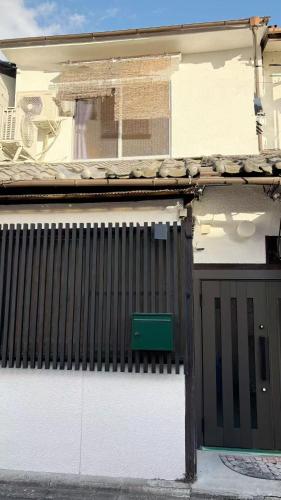 a white house with a gate and a green door at Meguli in Kyoto