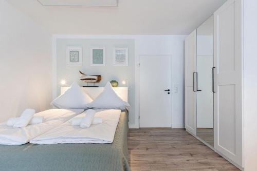 a white bedroom with a bed with white pillows at Sea la Vie - Seitlicher Meerblick zwischen Südstrand und Yachthafen in Fehmarn