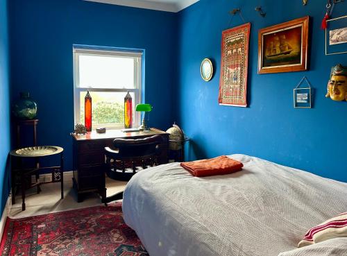 a blue bedroom with a bed and a desk and a window at Skyline Oasis in Portsmouth