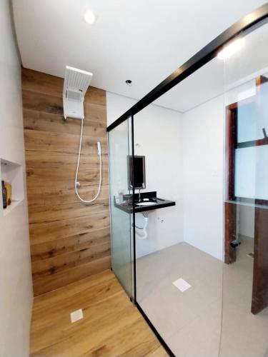 a room with a glass partition with a tv and a wall at Prime Flat Palladium Mar & Piscina in São Vicente