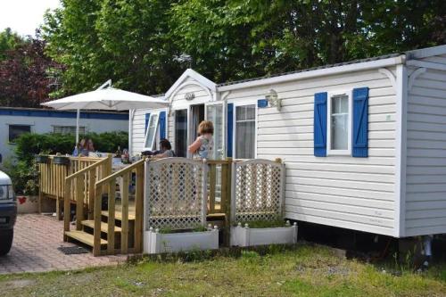 a white tiny house with people sitting at a table at ZEcamping 3 étoiles aire de jeux multi-activités in Toulouse