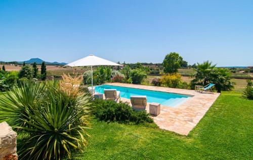 a pool with chairs and an umbrella in a yard at Son Artigues in Manacor