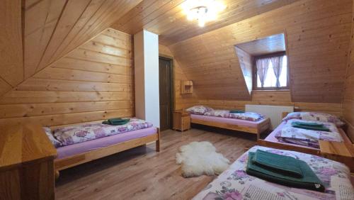 a room with two beds in a wooden cabin at Chata vo dvore in Osturňa