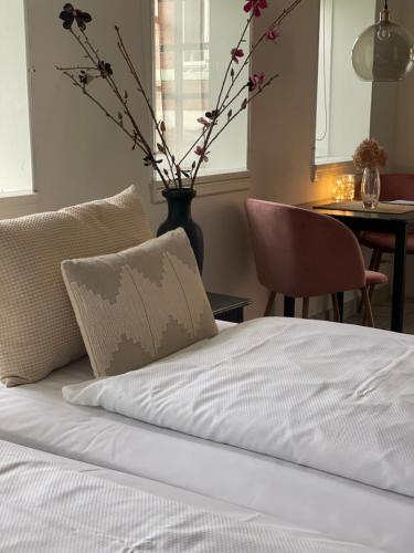 a bed with a pillow and a vase with flowers at Carlsminde ferielejlighed in Stenstrup