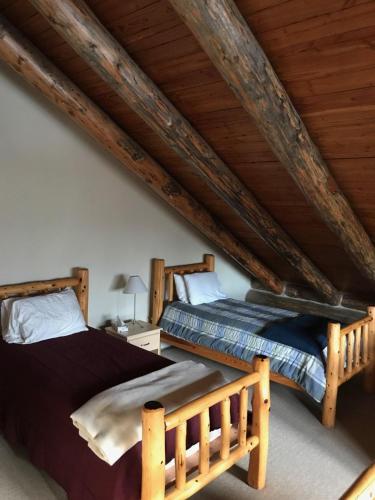 two beds in a attic bedroom with wooden ceilings at Spectacular Large Group Accommodations With Gallatin River Access! in Bozeman