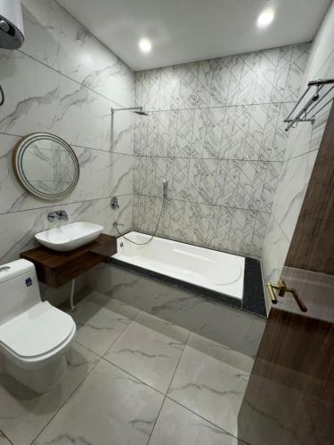a bathroom with a tub and a toilet and a sink at Nurem Hotel and Resort in Lalru