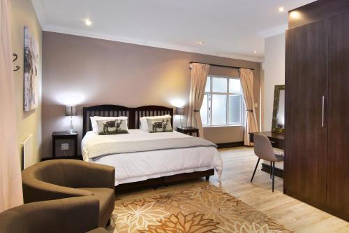 a bedroom with a bed and a desk and a chair at Sandown Guest House in Johannesburg