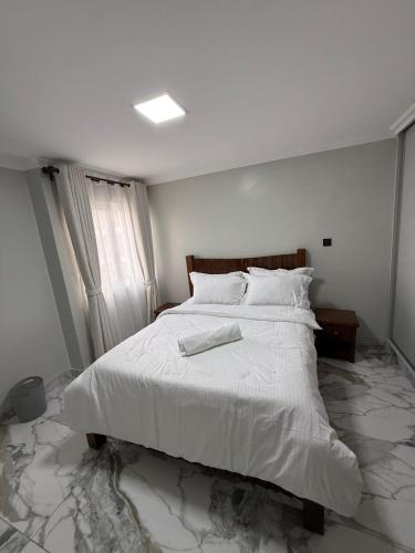 a bedroom with a white bed with marble floors at Sage Homes in Nairobi