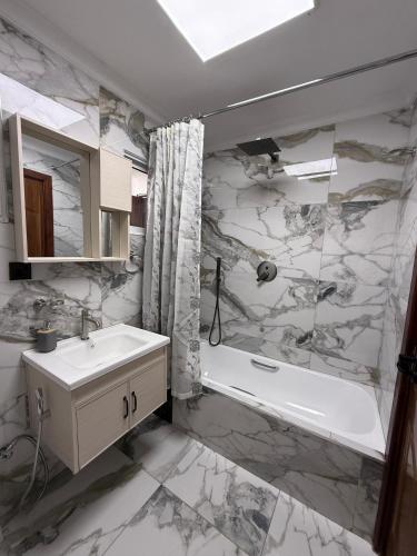 a bathroom with a tub and a sink and a bath tub at Sage Homes in Nairobi