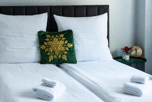 a bed with white towels and a green pillow at Ajncla in Katowice