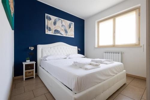 a bedroom with a white bed with a blue wall at IseoLakeRental - Panorama House in Parzanica