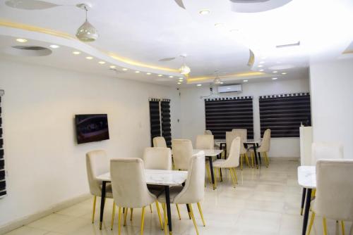 a dining room with white tables and chairs at Greystone Hotel in Asaba