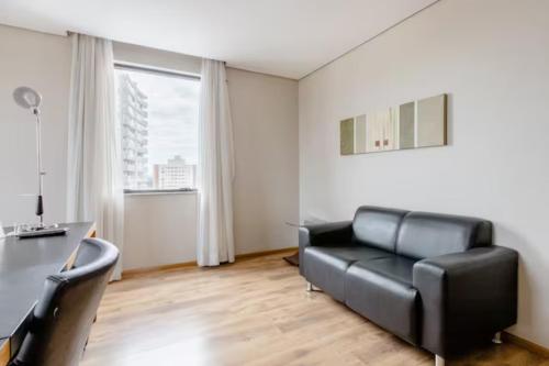 a living room with a black leather couch and a desk at Flat Osasco Trade Center in Osasco