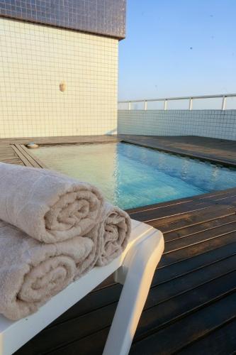 a swimming pool with a towel sitting on a deck at Cobertura Duplex a Beira-Mar de Capão da Canoa in Capão da Canoa