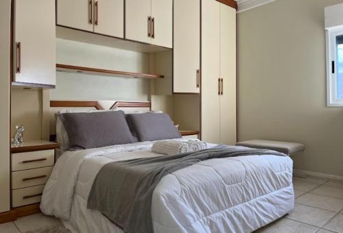 a bedroom with a large bed with white cabinets at Cobertura Duplex a Beira-Mar de Capão da Canoa in Capão da Canoa