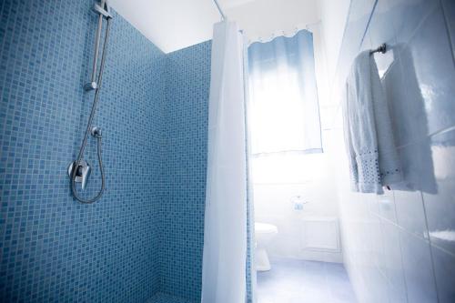 a blue tiled bathroom with a shower and a toilet at Appartamento Nettuno in Castellammare del Golfo