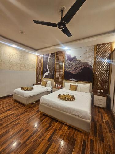 two beds in a room with a ceiling fan at Ambassador Suites in Dargai