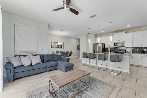 a living room with a blue couch and a kitchen at Storey Lake 4BR w/ Private Pool near Disney in Kissimmee