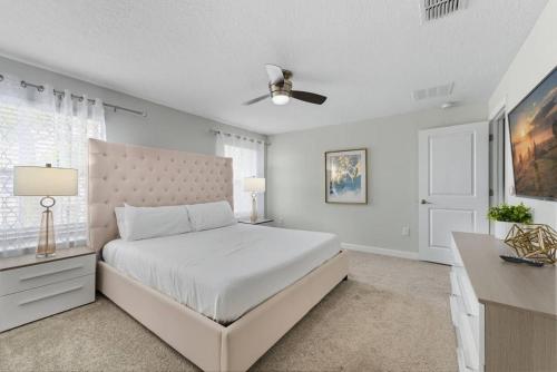 a white bedroom with a bed and a ceiling fan at Storey Lake 4BR w/ Private Pool near Disney in Kissimmee
