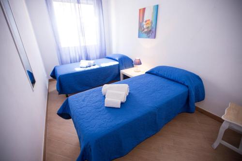 two beds in a small room with blue sheets at Appartamento Nettuno in Castellammare del Golfo