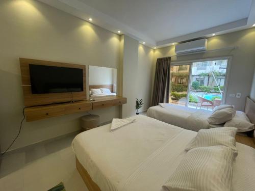 a hotel room with two beds and a flat screen tv at Florenza Khamsin Resort in Hurghada