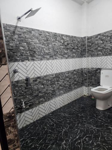 a bathroom with a toilet and a tile wall at HA Homes in Matale
