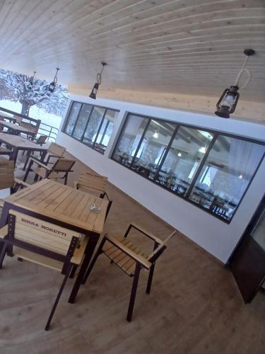 a table and chairs in a room with windows at Hanul Ibăștean in Brădeţelu