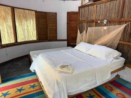 a bedroom with a bed with a white blanket at Las Cabañas del Rio in Minca
