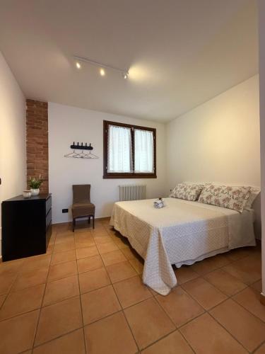 a bedroom with a bed and a chair and a window at La Dimora dei Cri in Cona