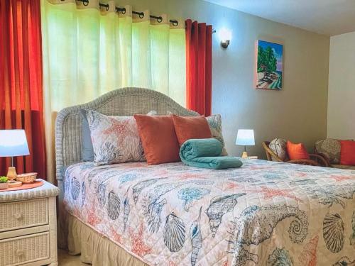 a bedroom with a bed with colorful pillows on it at Tropical superbe views in Saint Johnʼs