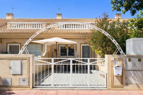 a gate in front of a house with an umbrella at Casa Moolio - Private Holiday Home with Pool Access, Walk to Beach & Restaurants in Los Alcázares