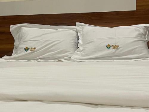 two pillows on a bed with white sheets at Casal stay in Mannārakkāt