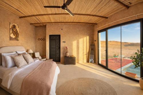 a bedroom with a bed and a large window at Desert Wonders Camp in Ḩawīyah