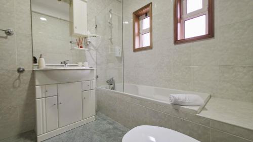 a bathroom with a toilet and a sink and a tub at Martins House in Vila Viçosa