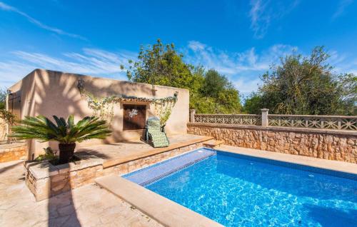 a swimming pool in a backyard with a stone wall and a fence at Moli De Ca N'orell in Santanyi