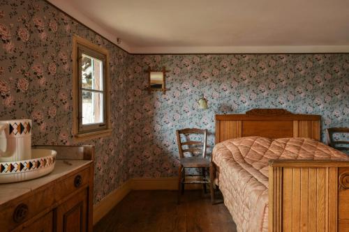 a bedroom with a bed and a window and a chair at Chez Oma, La petite ferme in Weinbourg