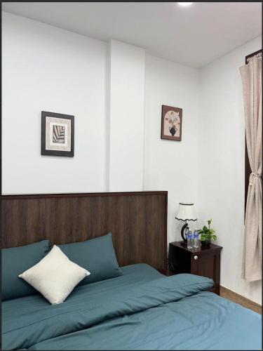 a bedroom with a blue bed with a wooden headboard at Ovana Homestay in Phan Thiet
